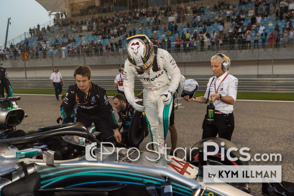 Angela membantu Lewis Hamilton masuk ke mobil Mercedes F1-nya di grid