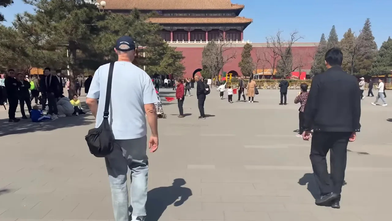 Tourists walking along the entrance area with the Forbidden City behind them