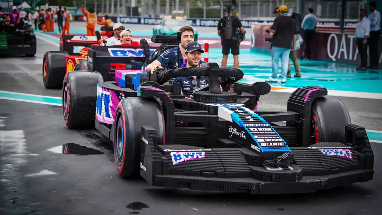 drivers riding life-size Lego-style Formula 1 cars during the drivers' parade on a wet track