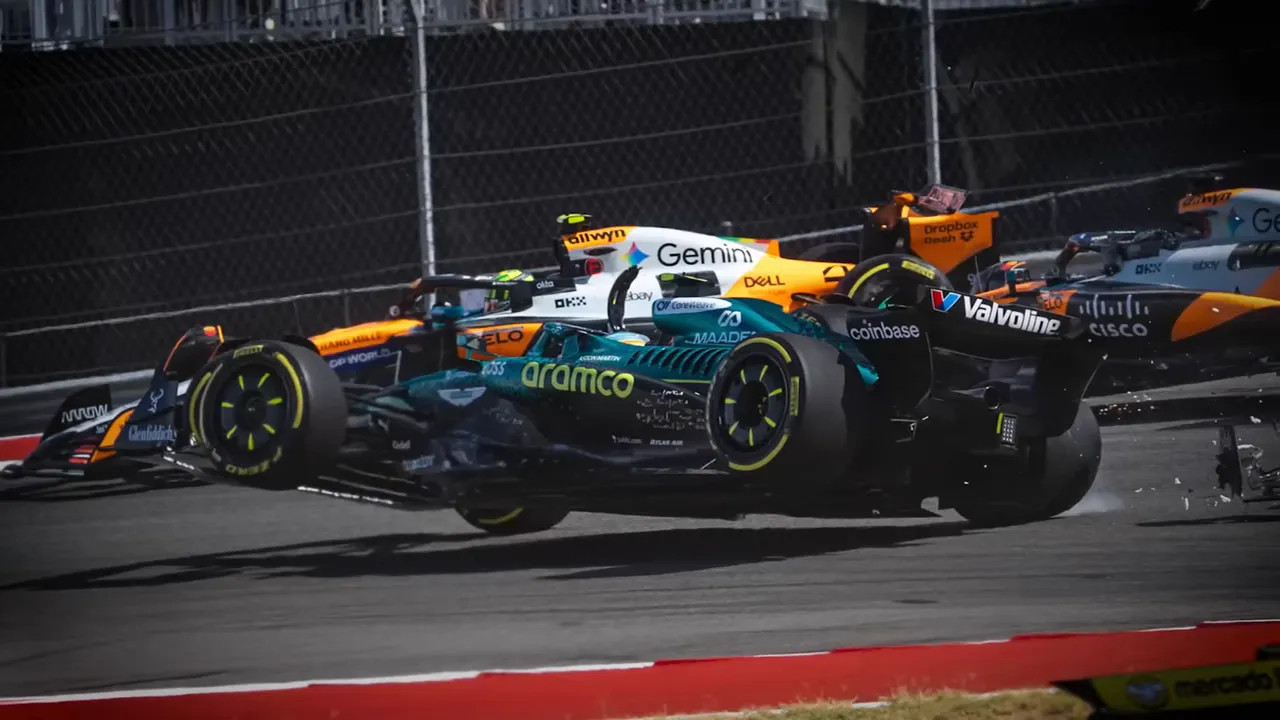 Two Formula 1 cars tangled in wheel-to-wheel contact with debris visible on the track