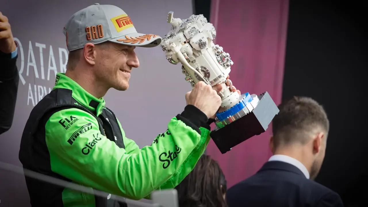 Driver lifting a trophy on the podium while celebrating a race result