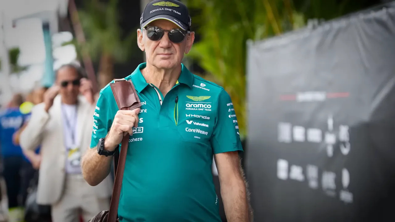Adrian Newey walking through the paddock in a green Aston Martin team shirt and cap
