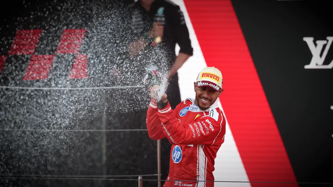 Lewis Hamilton in Ferrari race suit spraying champagne on the Monaco podium