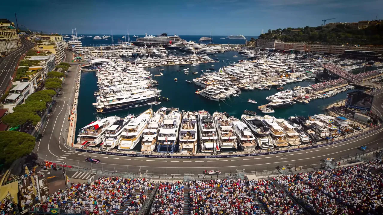 Wide aerial view of Monaco harbor, yachts, grandstands, and the circuit around Port Hercule