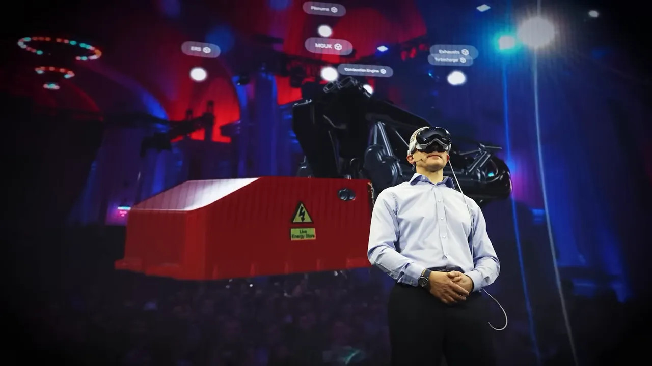 Presenter wearing a VR headset stands in front of a red engine cover and engine components projected on the screen