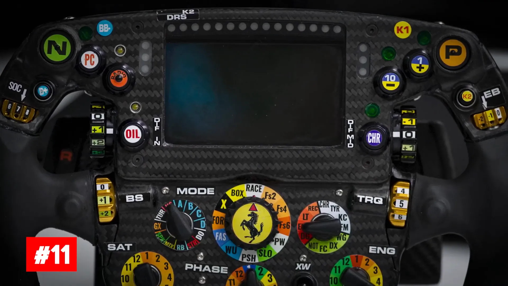 Driver handling a complex F1 steering wheel full of buttons