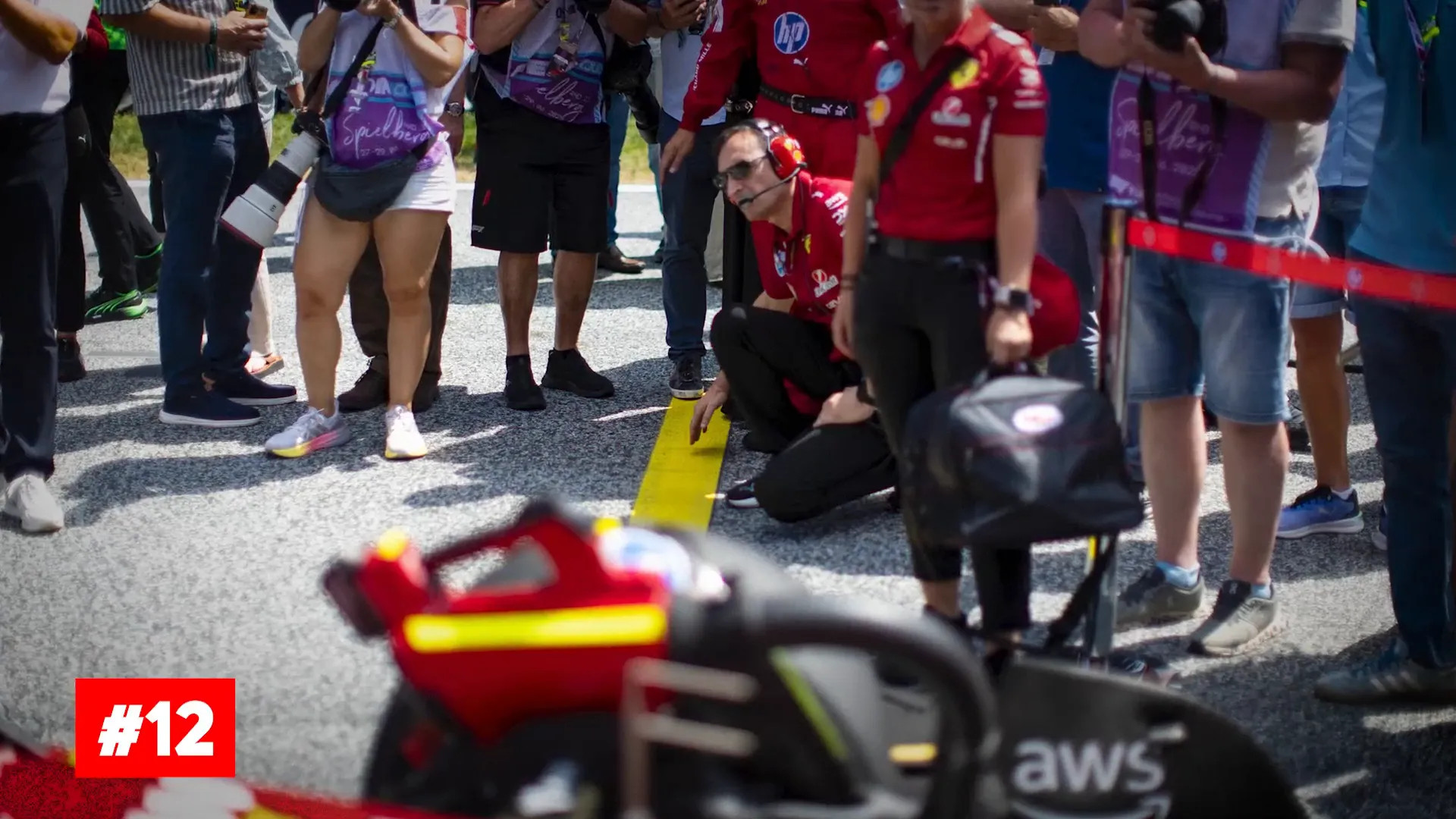 F1 car positioned on the grid with man making final checks