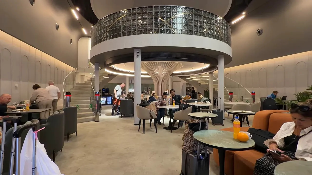 Airport lounge with tables, upholstered seating and a circular upper level