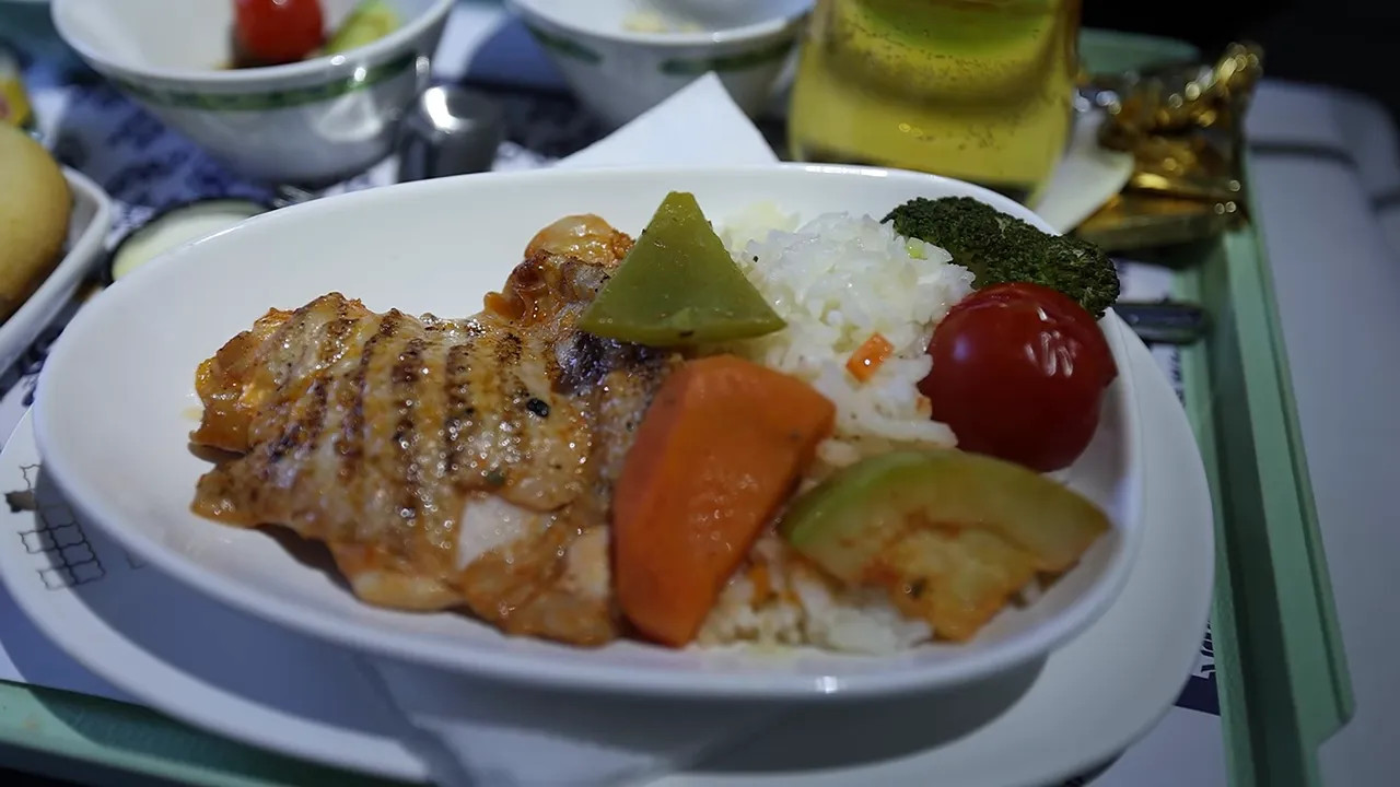 Grilled chicken with rice and vegetables on an airline meal tray