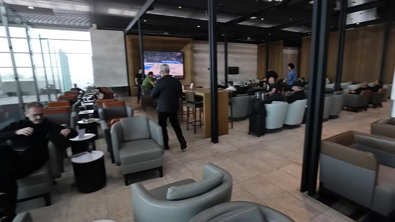 LATAM airport lounge seating area with armchairs, TV and large windows