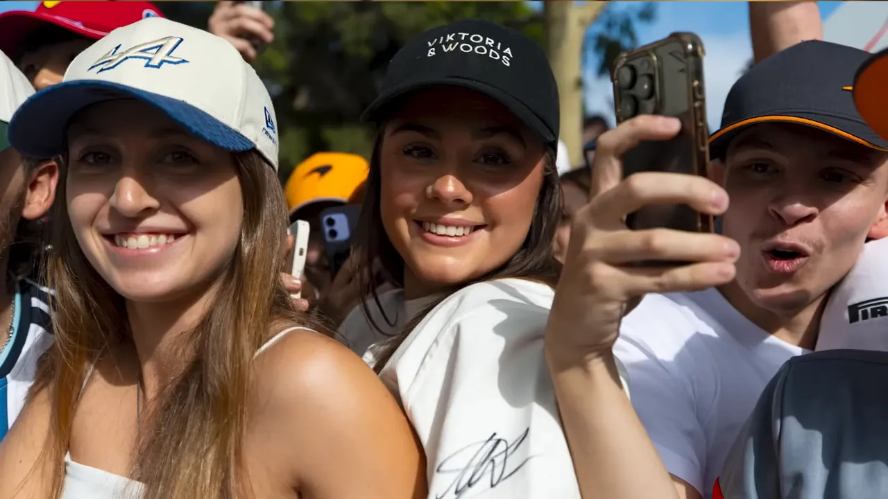 Three smiling young Formula 1 fans taking a selfie outdoors