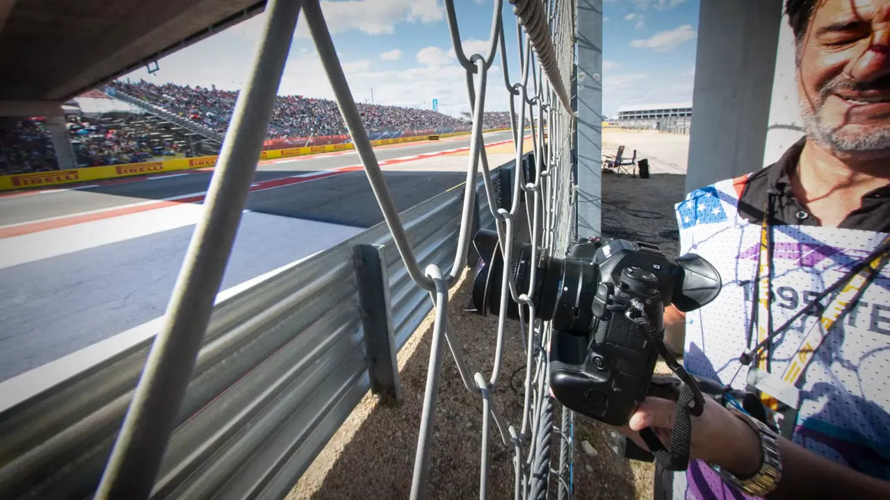 Photographer demonstrating lens-through-fence technique