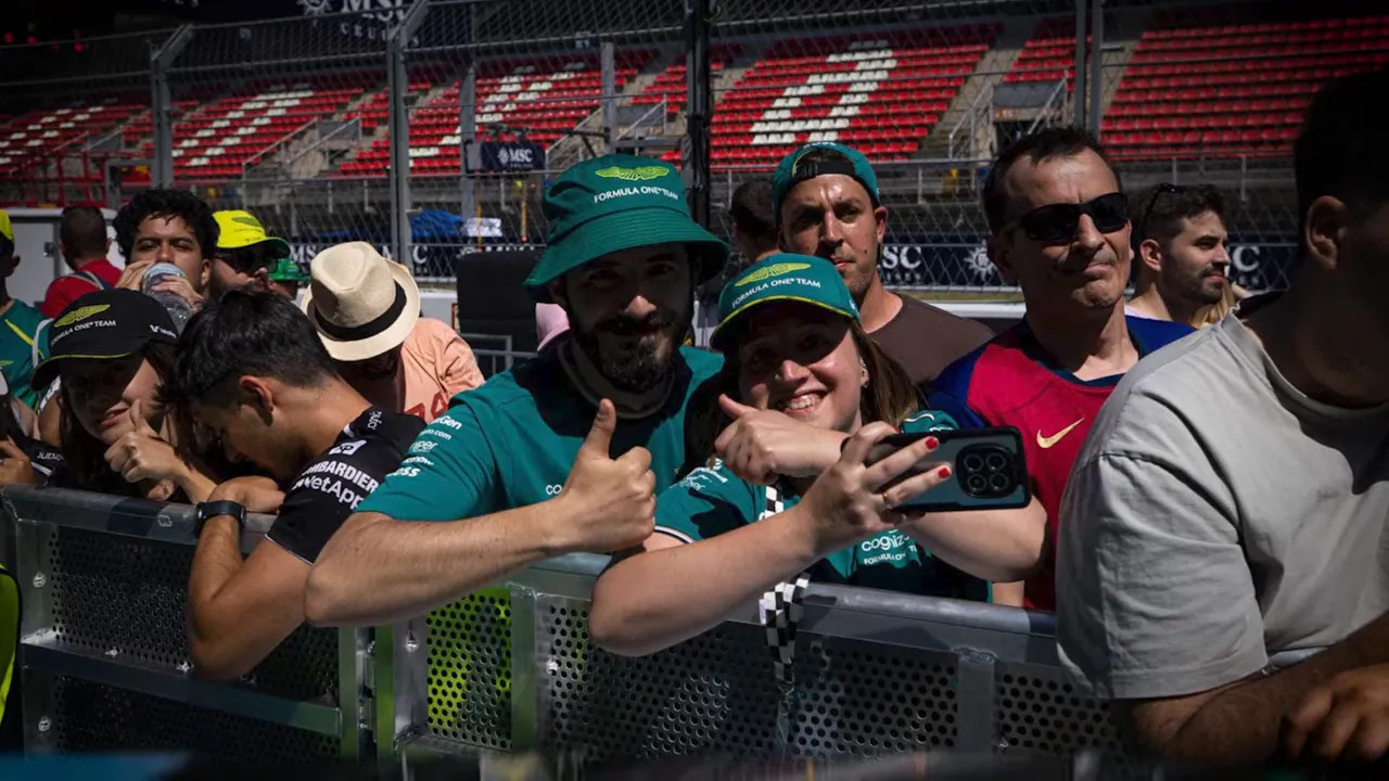 fans in green Aston Martin gear leaning on barrier with aramco formula one team banner