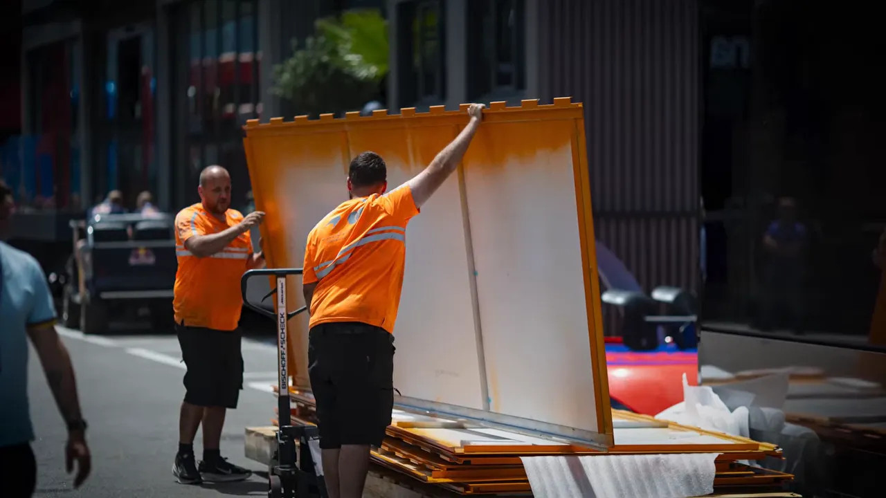 large black and orange McLaren hospitality structure being assembled with lift platforms
