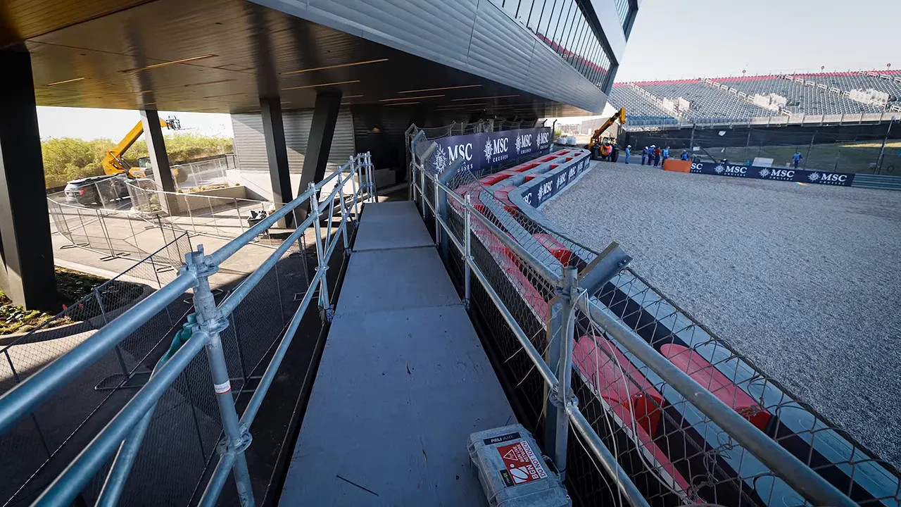 Narrow raised walkway with metal railings beside the new circuit building