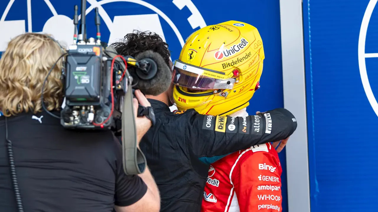 Lando Norris hugging Lewis Hamilton in parc ferme with camera operator nearby