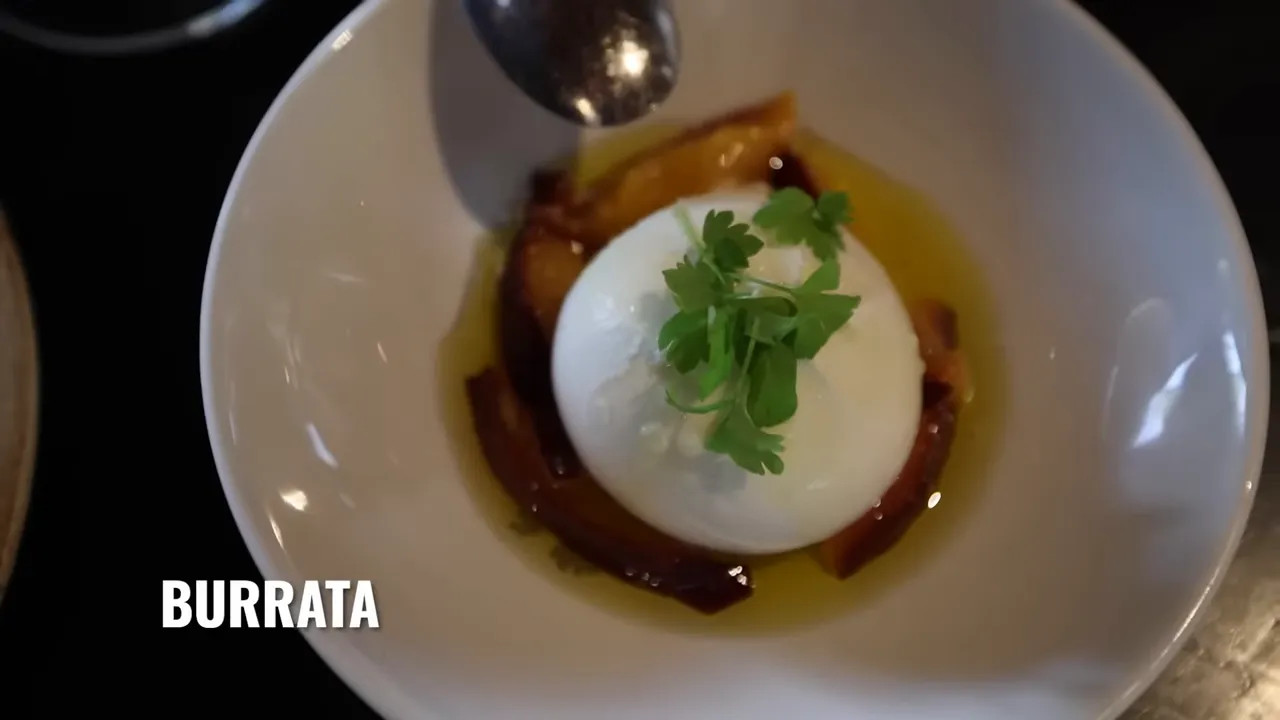 Burrata served with herbs and rich sauce on a white plate