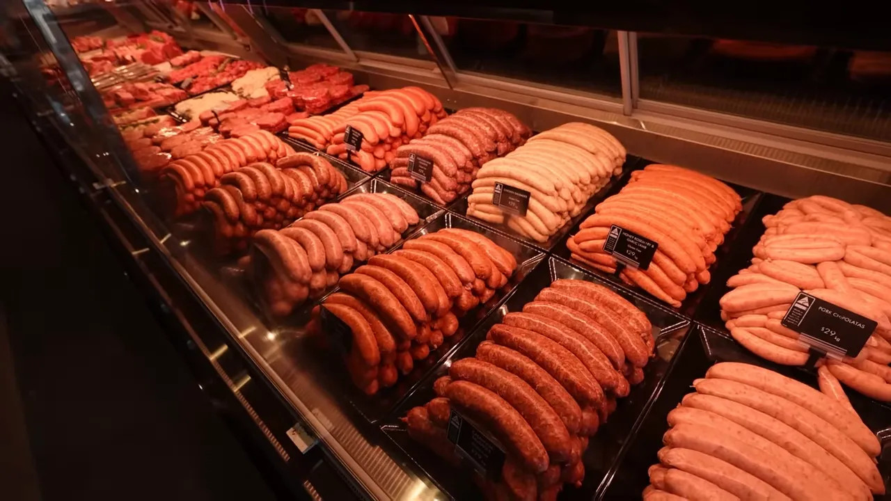 Close-up meat and sausage display case with neatly arranged sausages on trays