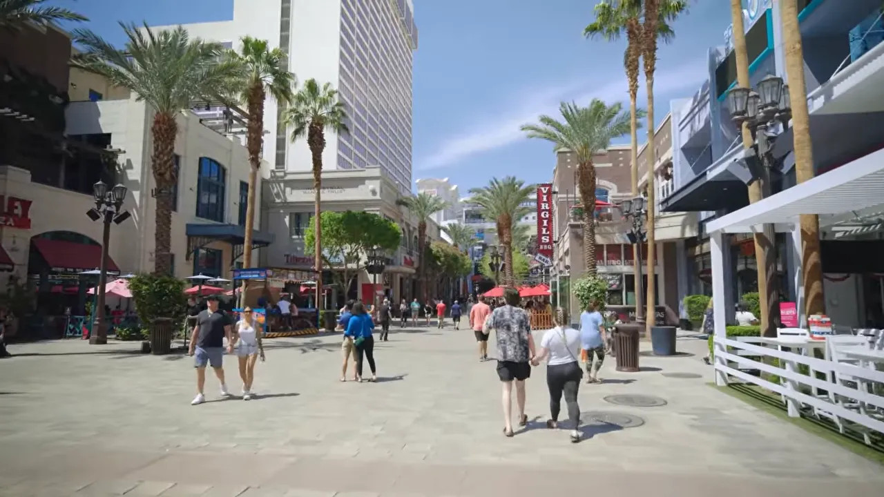 People walking along the Las Vegas Strip with palm-lined hotels