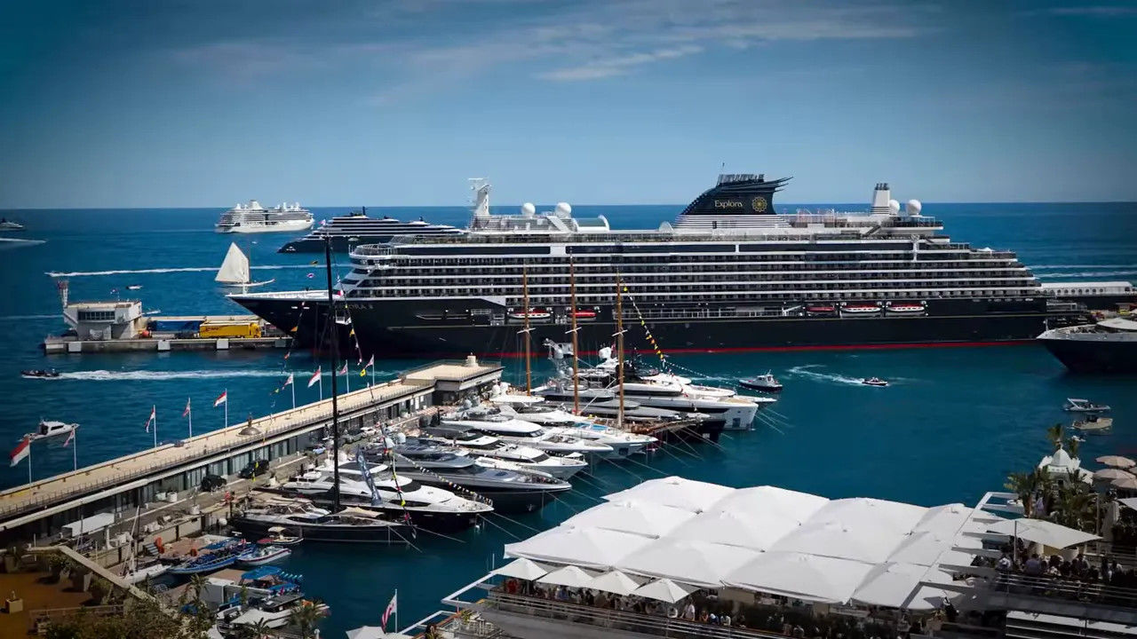 Large cruise ship docked beside Monaco harbour with yachts and hospitality structures below
