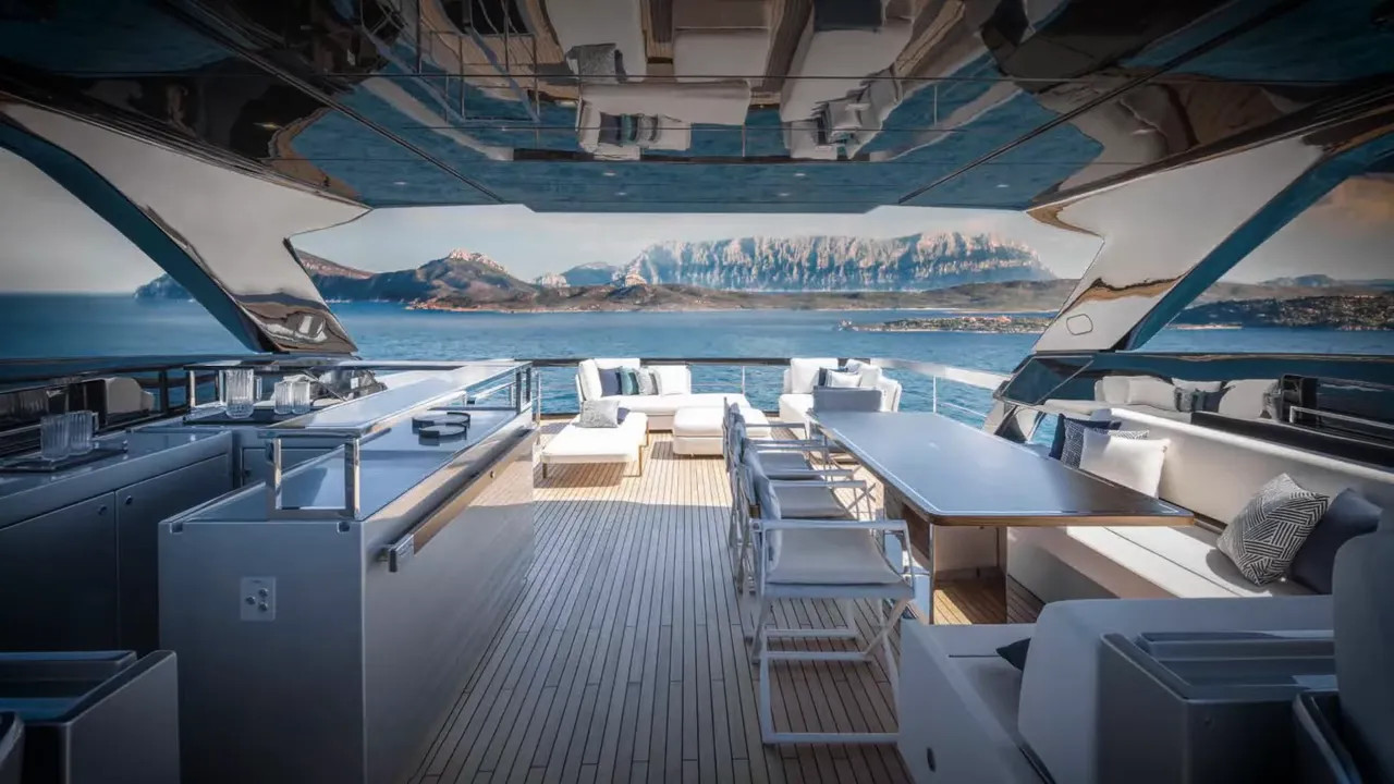 Open aft deck of a luxury yacht with dining area, seating, and sea view