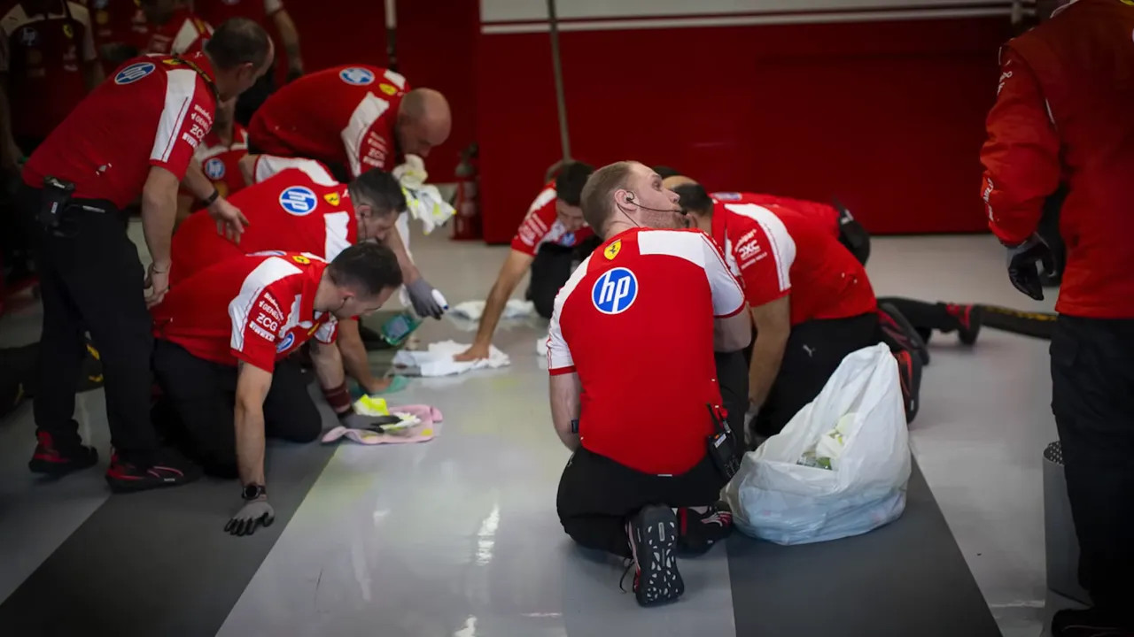Garage crew on their knees cleaning and scrubbing skid marks from the floor