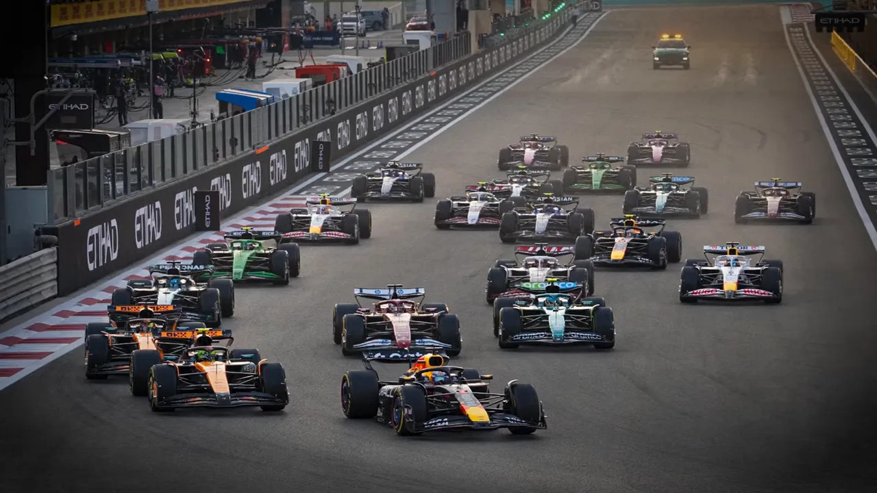 Pack of Formula 1 cars racing down the start straight in close formation
