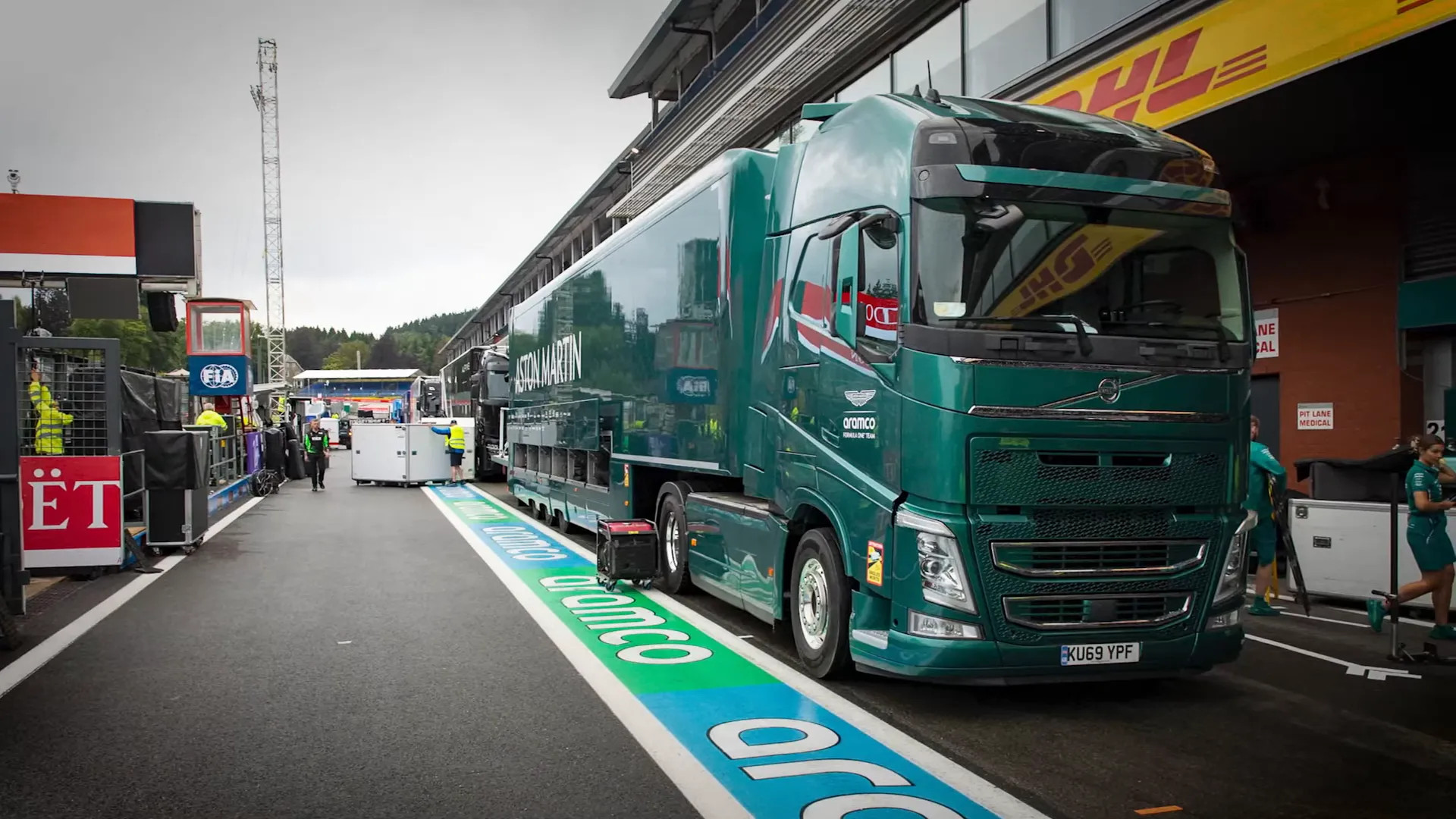 Branded team transporters and rented DHL trucks lined up in the paddock