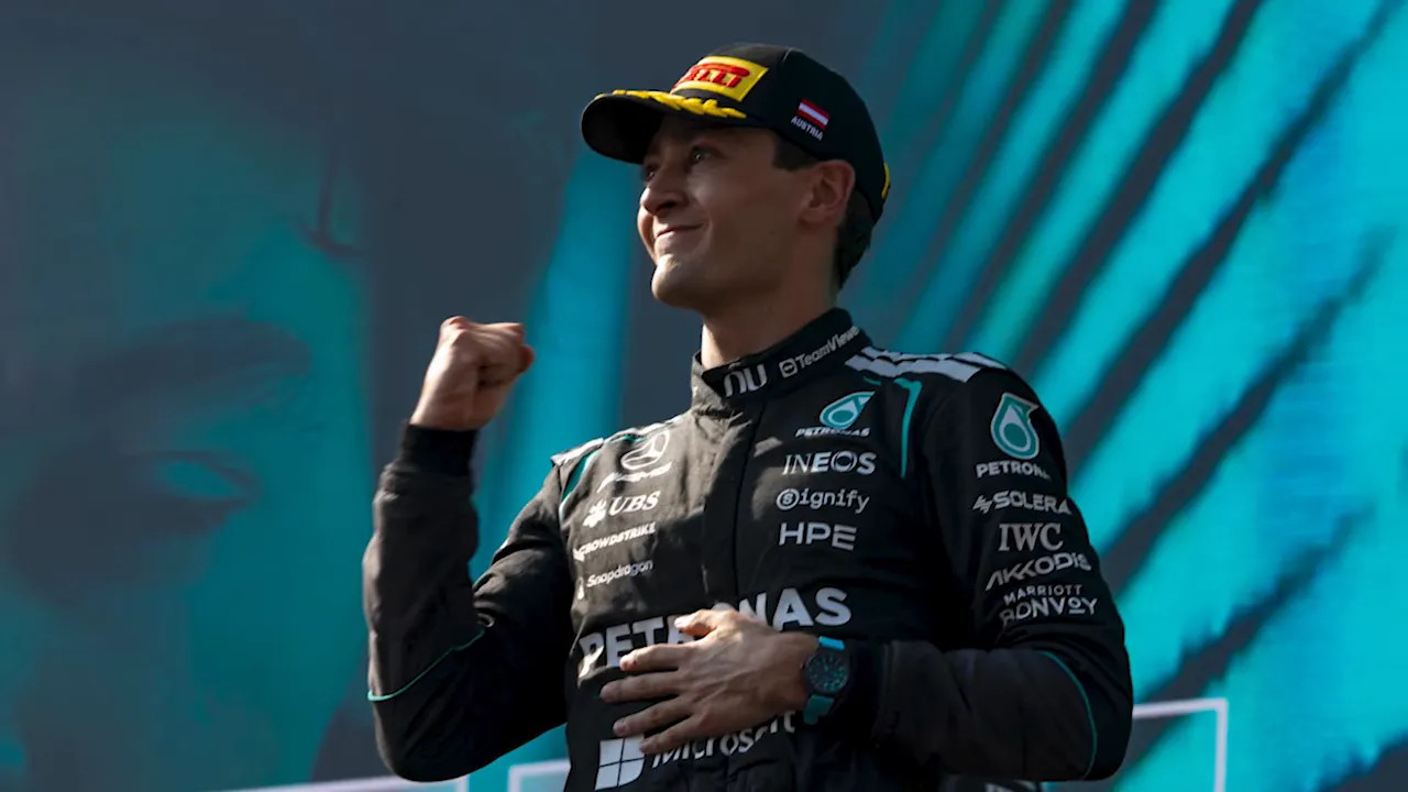 George Russell on stage in Mercedes race suit making a fist pump