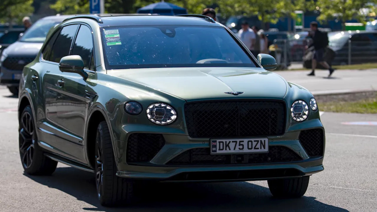 Green Bentley SUV driving in the paddock area