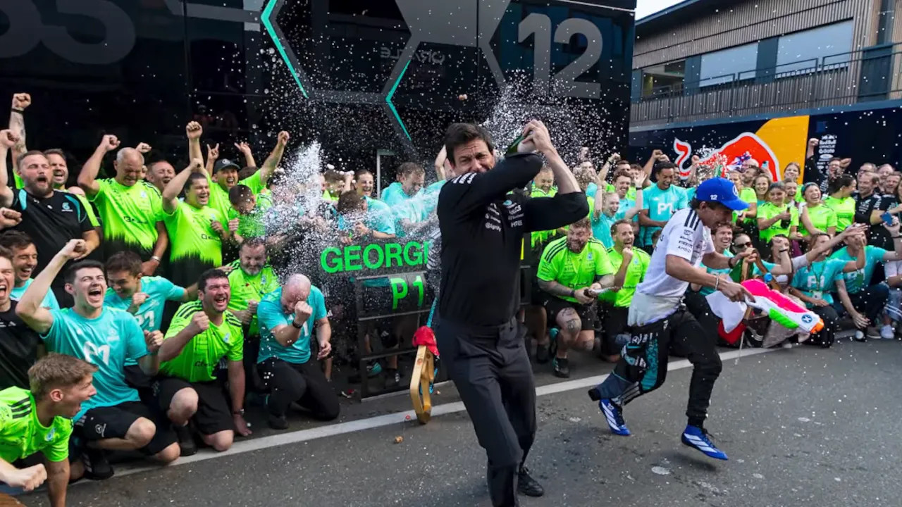 Toto Wolff spraying champagne in front of the celebrating Mercedes team