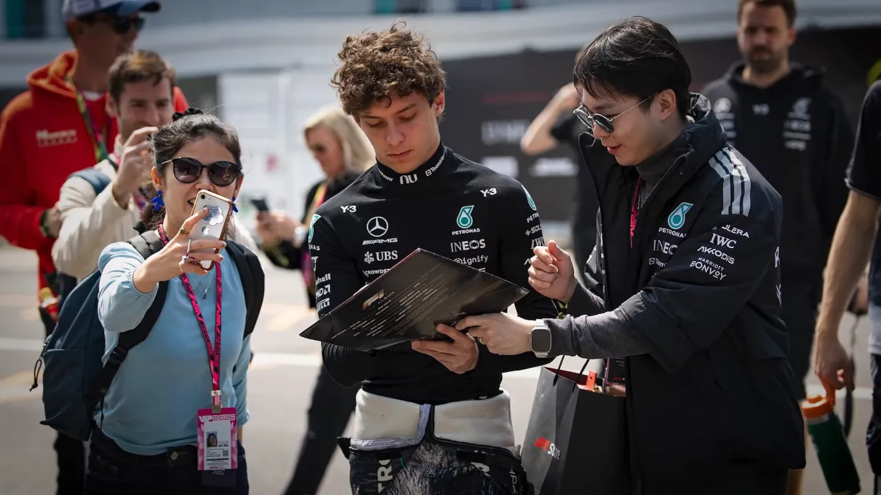 Andrea Kimi Antonelli signing an autograph while standing with fans in the paddock