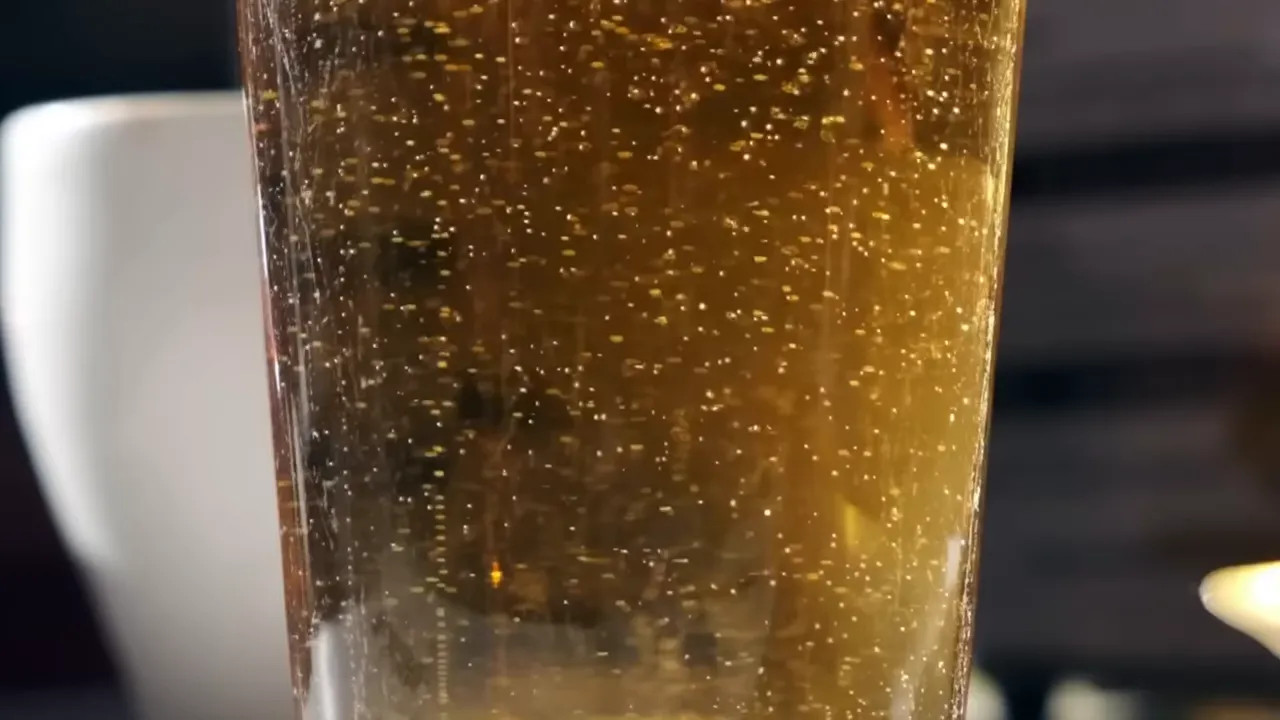 Close-up of tiny bubbles rising through golden beer in a glass