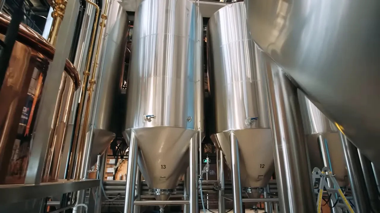 Tall stainless steel conical fermentation tanks inside the brewery