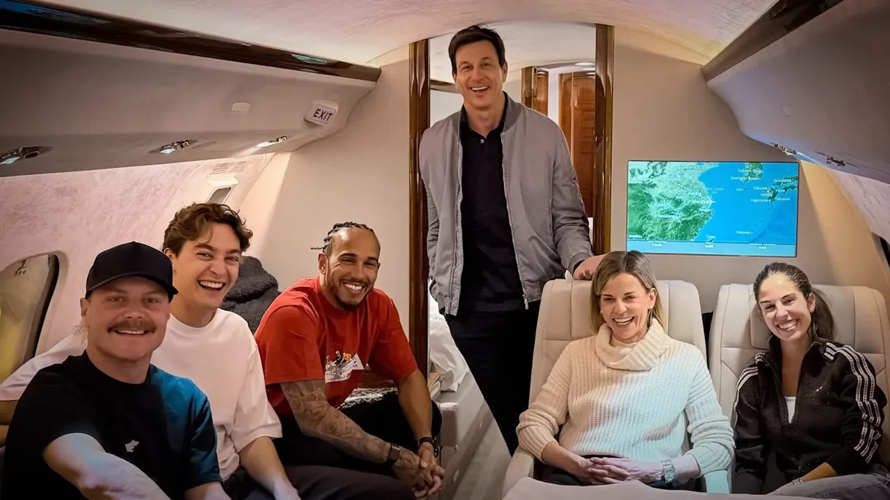 Group photo inside a private jet cabin with crew and passengers seated and a navigation screen