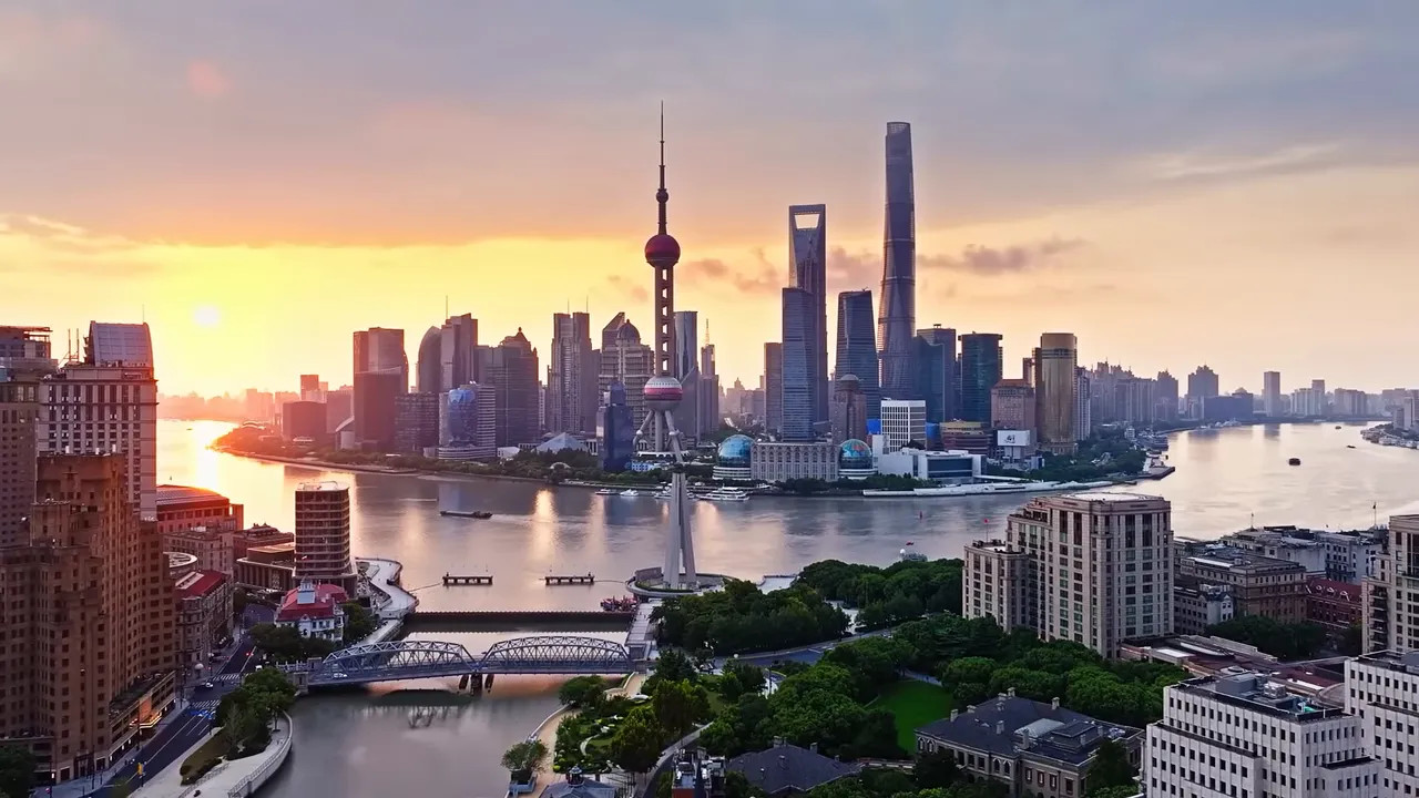 Shanghai skyline at sunrise with the Oriental Pearl Tower and modern high-rise buildings along the Huangpu River
