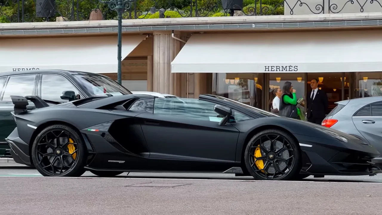 Black Lamborghini parked in front of a Hermes storefront