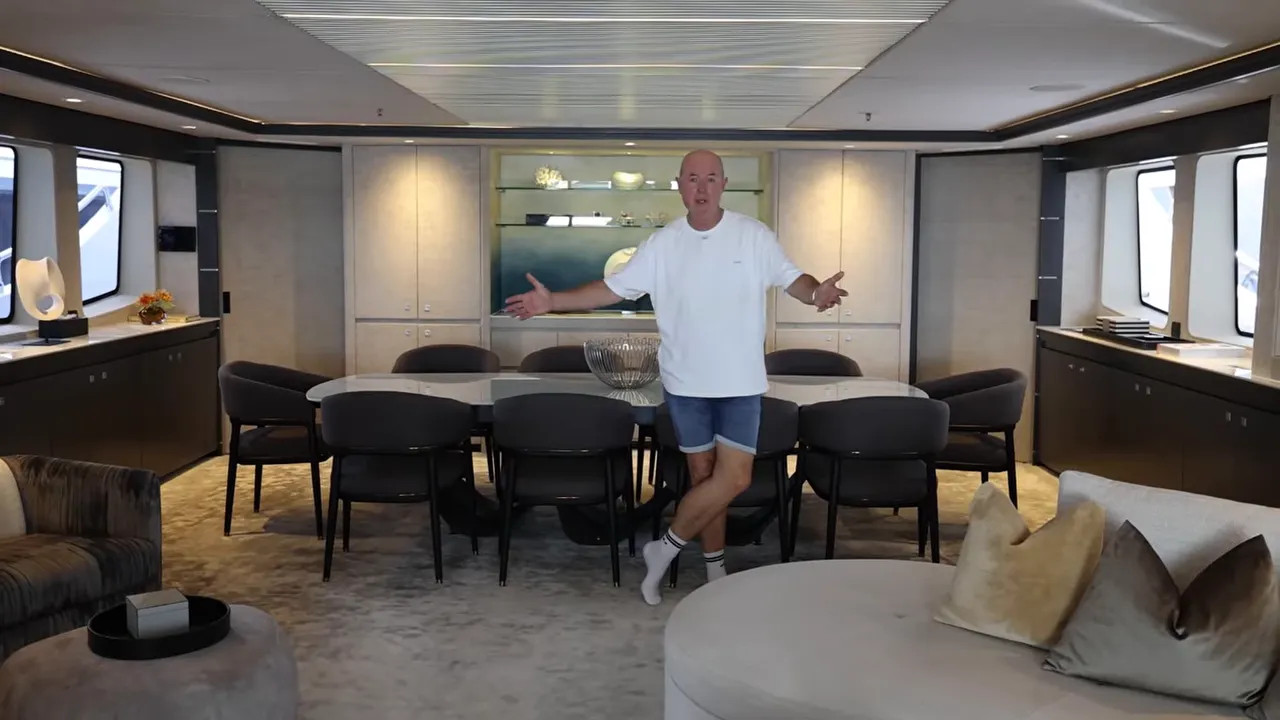 Large yacht salon with long sofa, bar stools, and lounge area