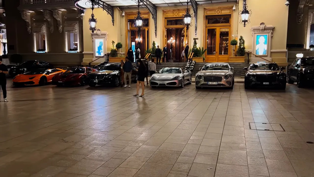 Line of supercars parked outside the grand casino entrance at night