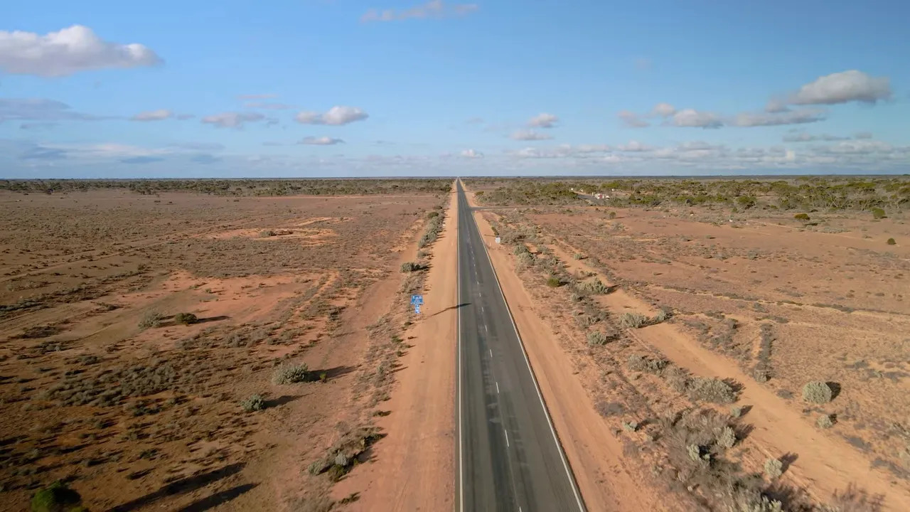 Aerial view of a perfectly straight highway through flat scrubland