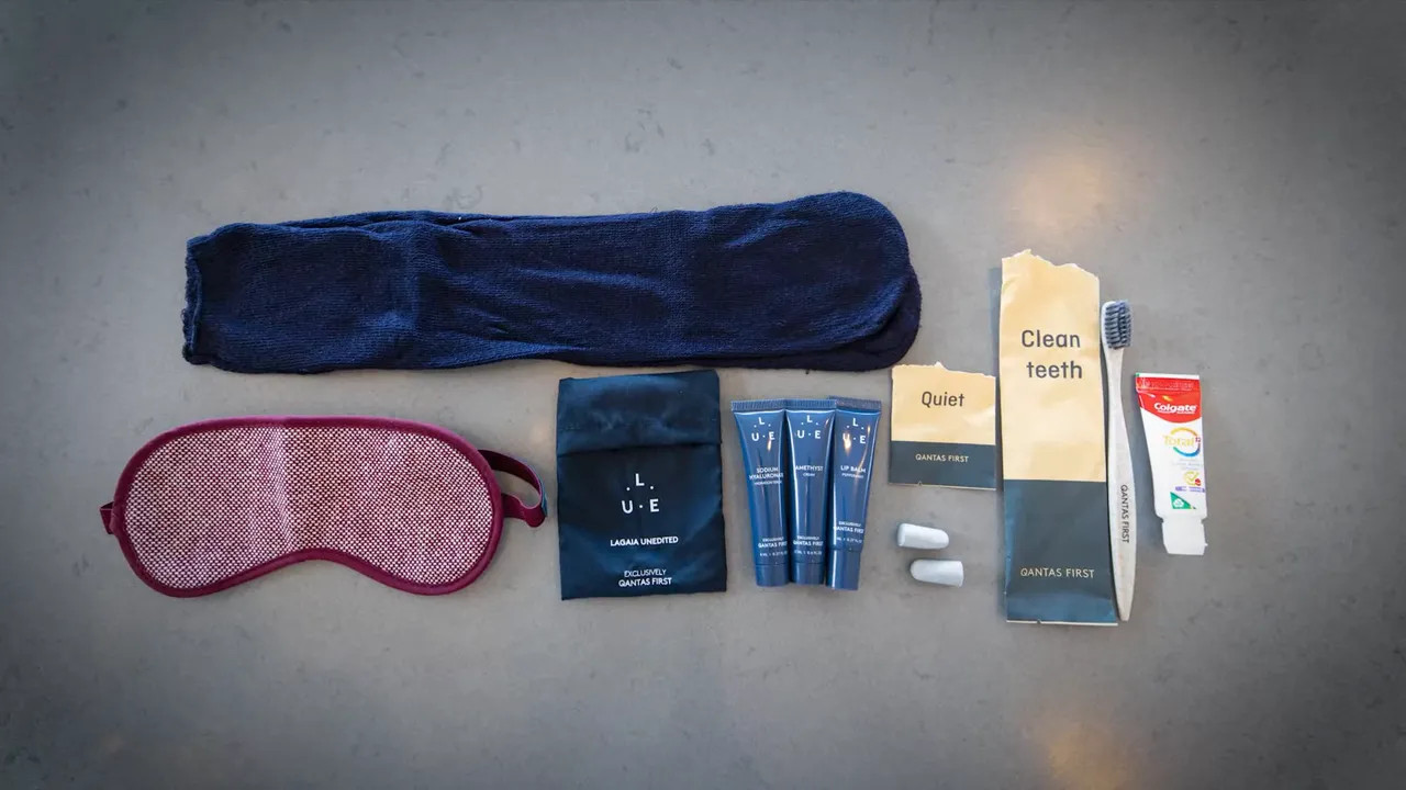 First‑class amenity items including branded eye mask, skincare tubes, earplugs and toothbrush with 'Qantas First' packaging.