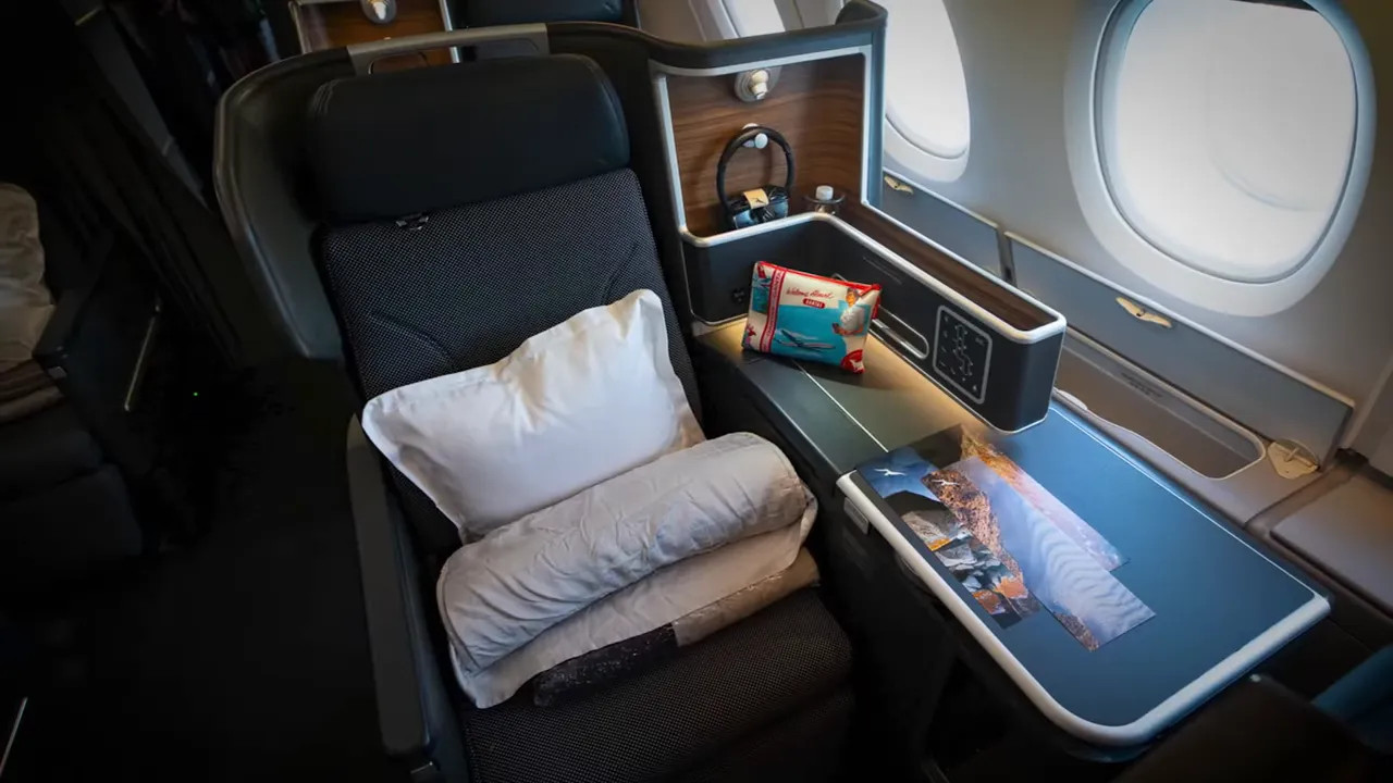 Qantas A380 business-class window seat showing tray table, pillows and storage