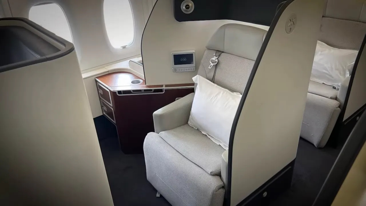 Qantas first-class suite with large armchair-style seat, pillow and wooden side console
