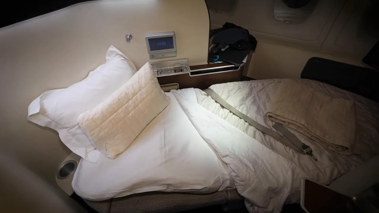 Well‑made lie‑flat seat bed with pillow, blanket and seatbelt arranged on the mattress