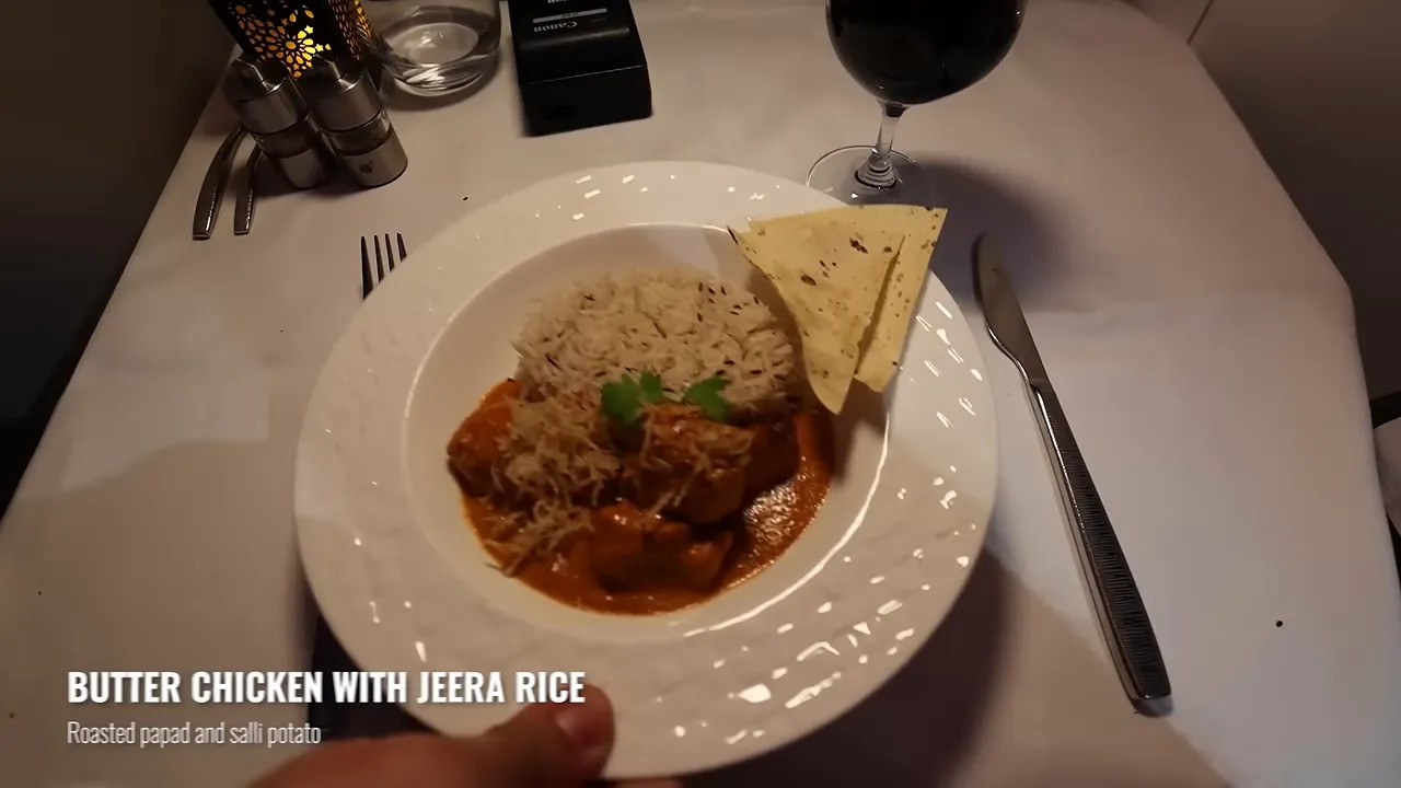 Butter chicken with jeera rice and flatbread on a white plate
