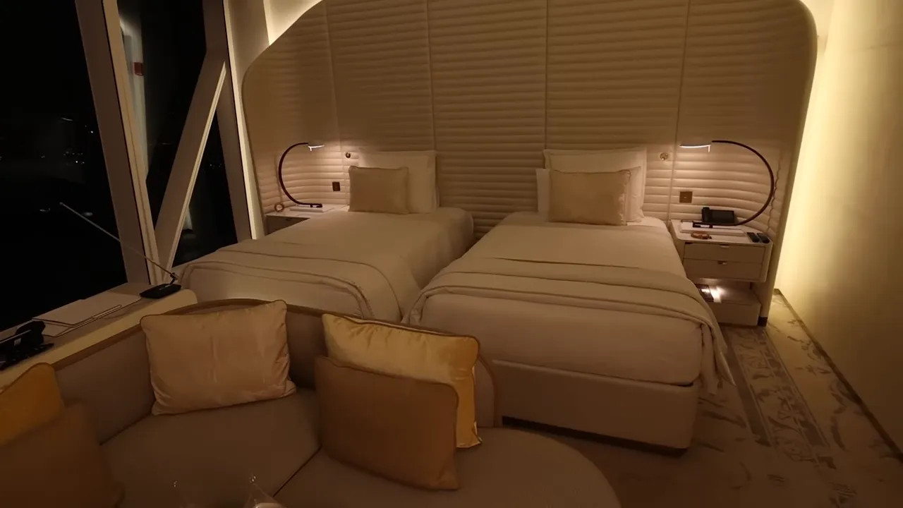 Ship cabin with twin beds, curved padded headboard and a small lounge area
