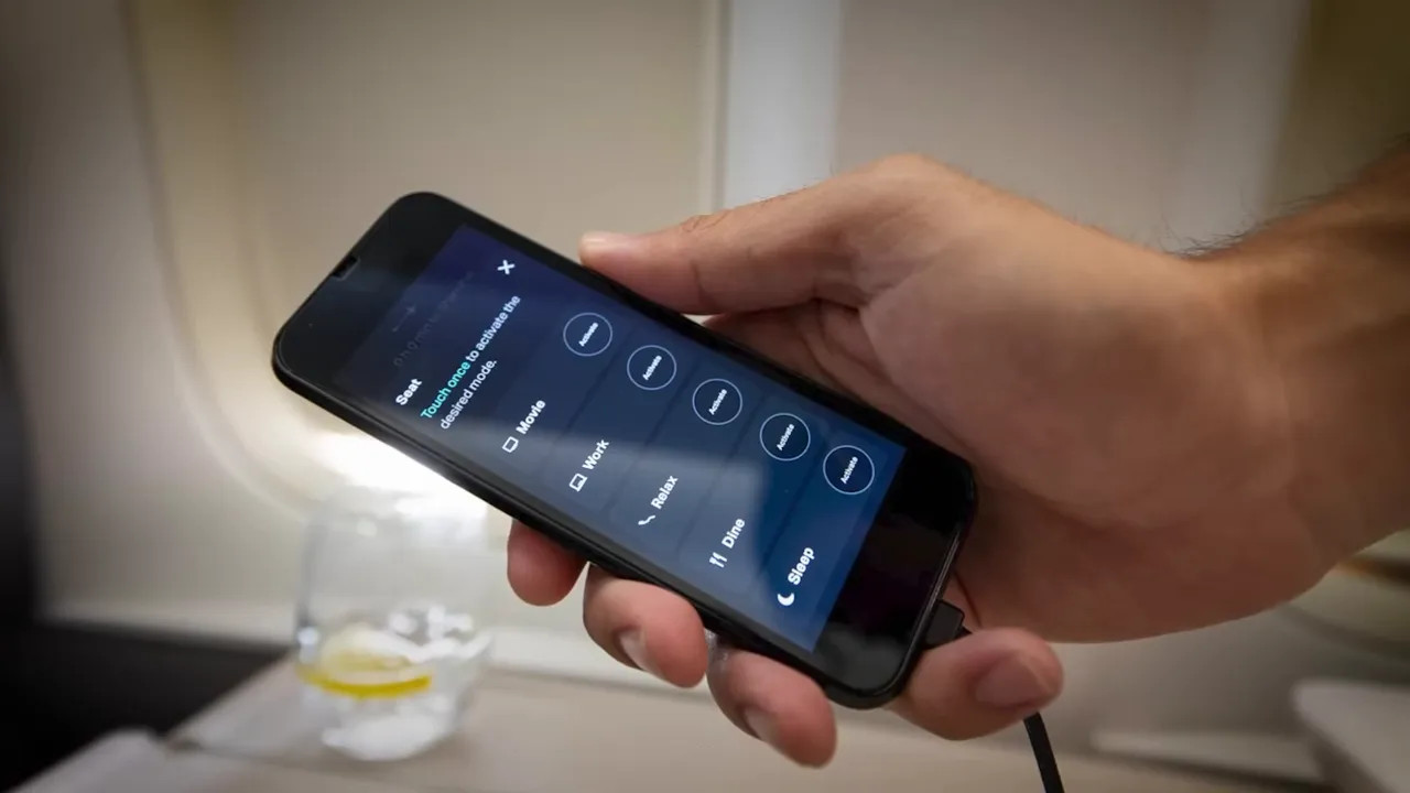 Handheld tactile remote showing seat modes (Sleep, Dine, Relax) in the Cathay Aria Suite