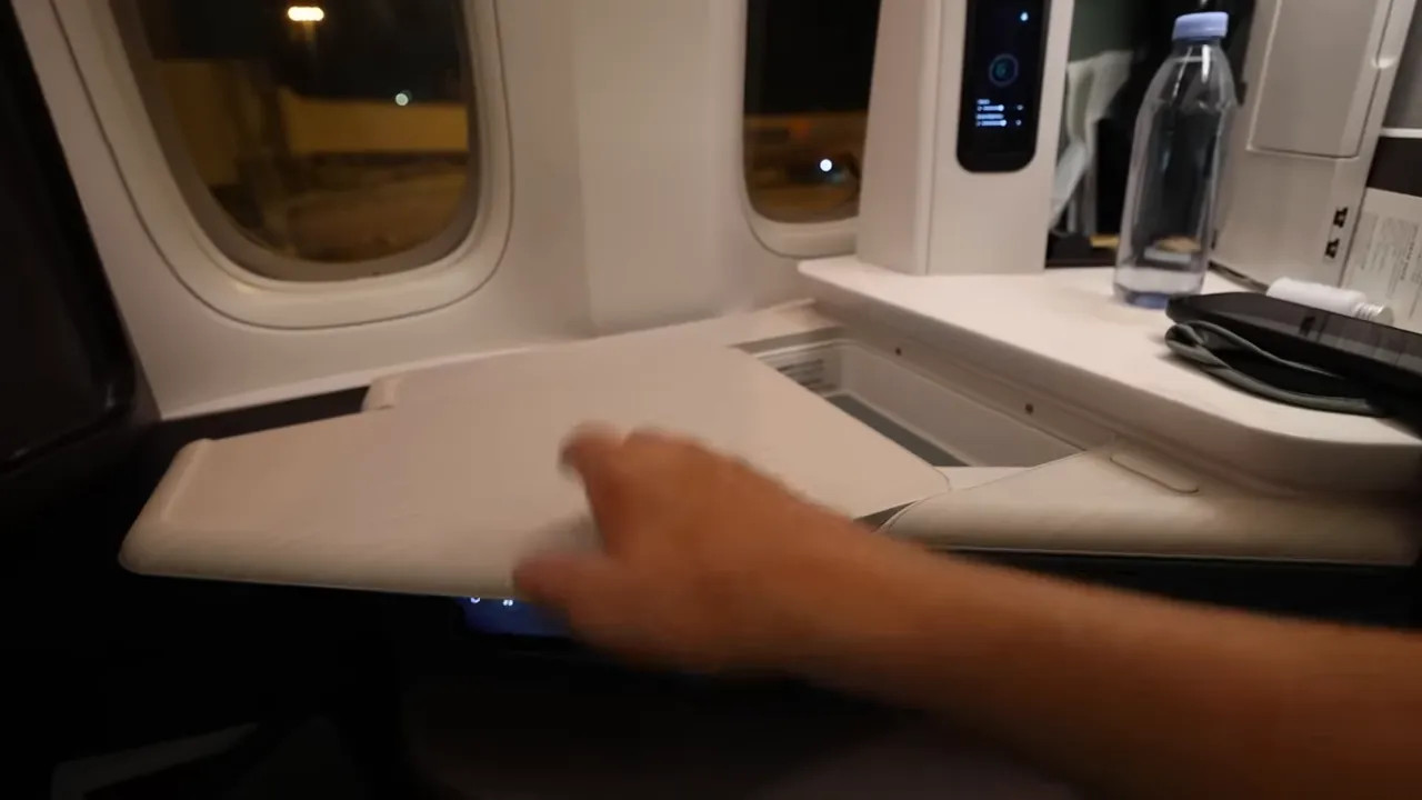 Left armrest and fold-out tray being demonstrated, showing how it becomes part of the bed platform in the Aria Suite