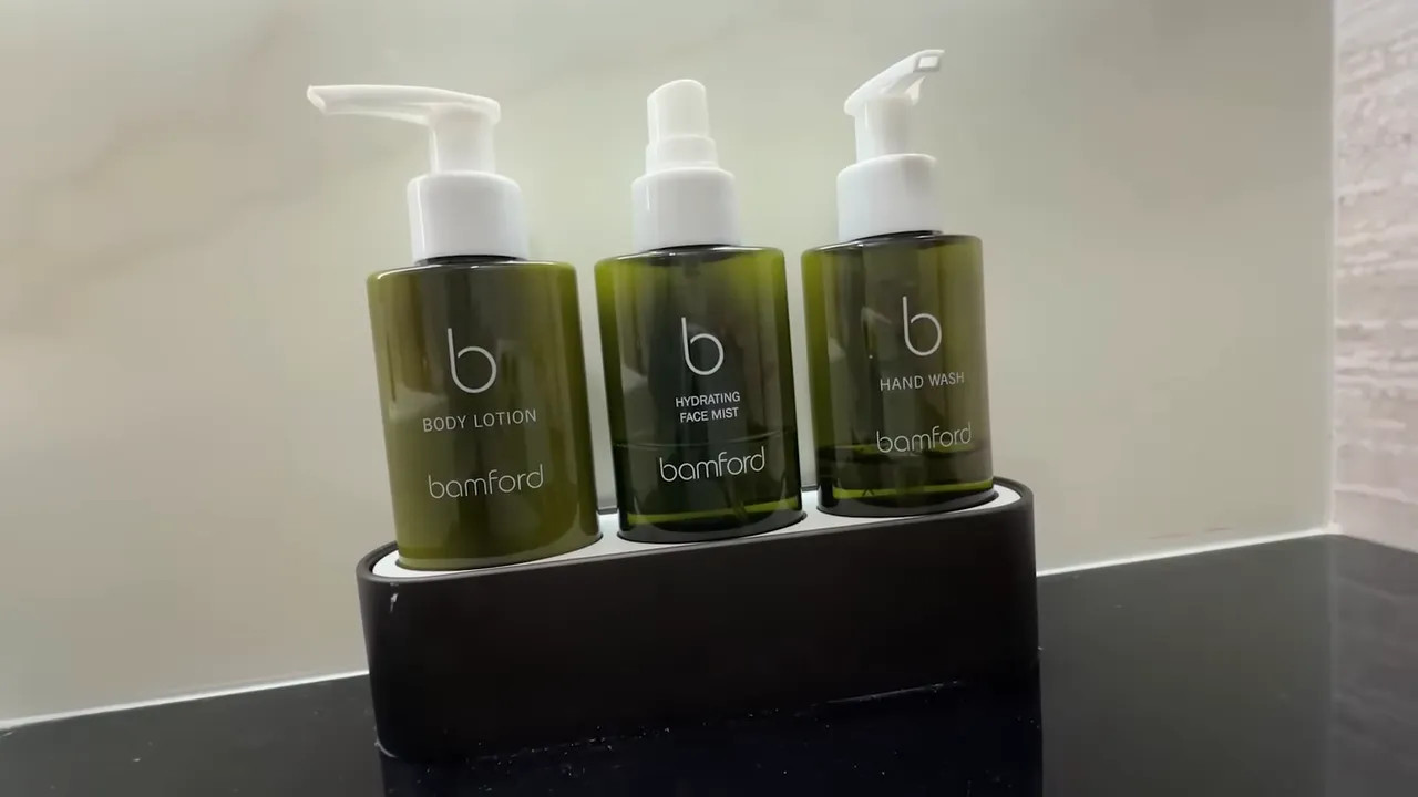 Three Bamford amenity bottles labeled hand wash, hydrating face mist and body lotion on a lavatory counter
