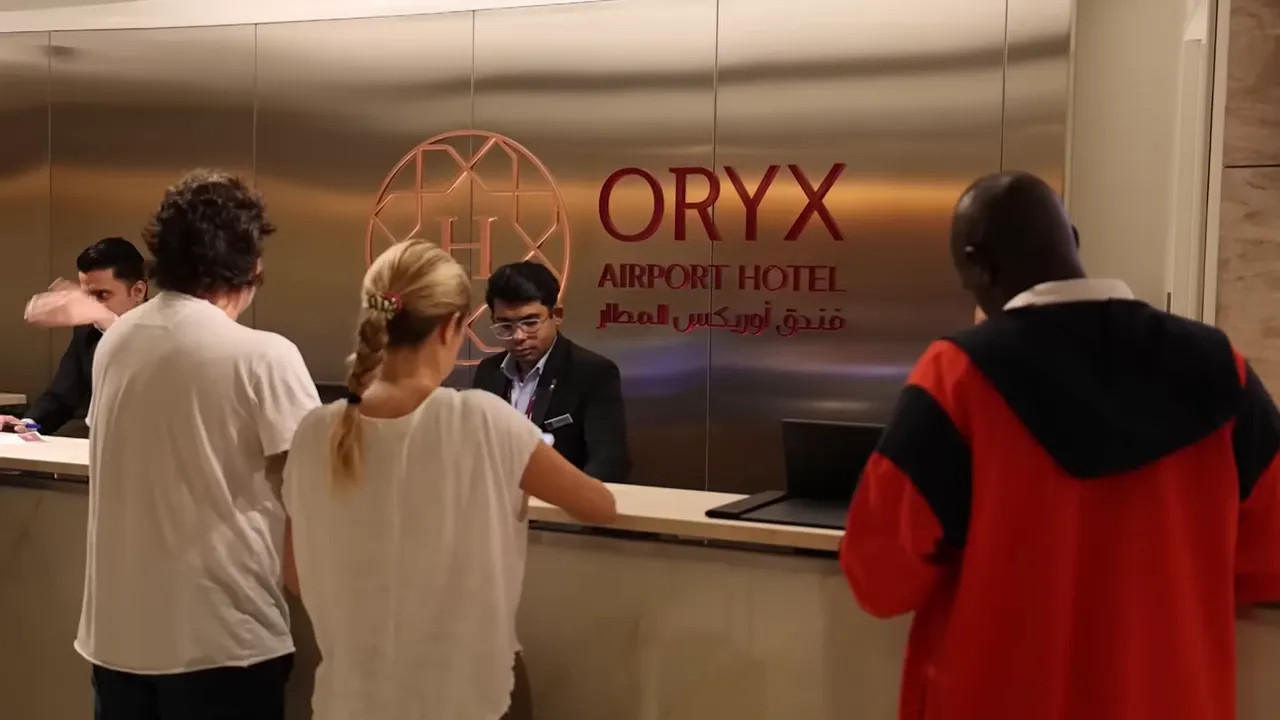 Guests checking in at the Oryx Airport Hotel reception desk with ORYX logo on the wall